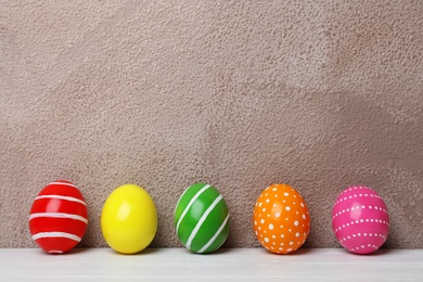 Decorated Easter eggs on table near color wall. Space for text