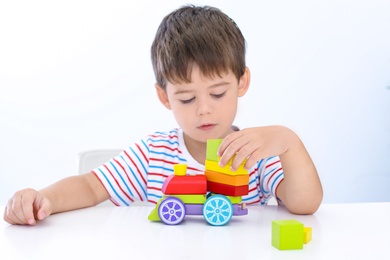 Little boy playing with toy at white table