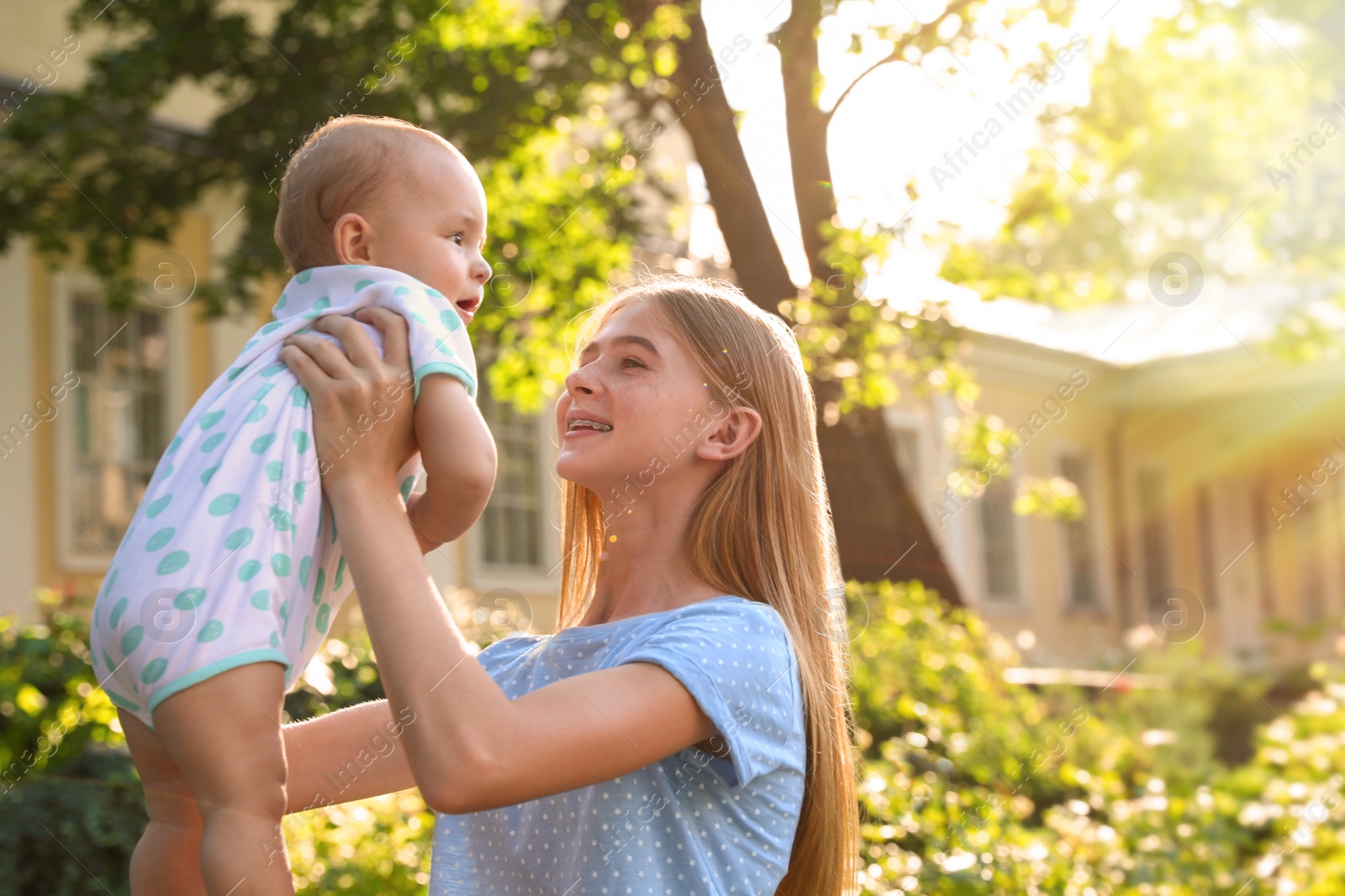 Photo of Teen nanny with cute baby outdoors on sunny day