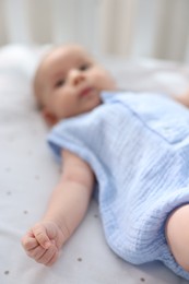 Photo of Cute little baby lying in crib at home, selective focus