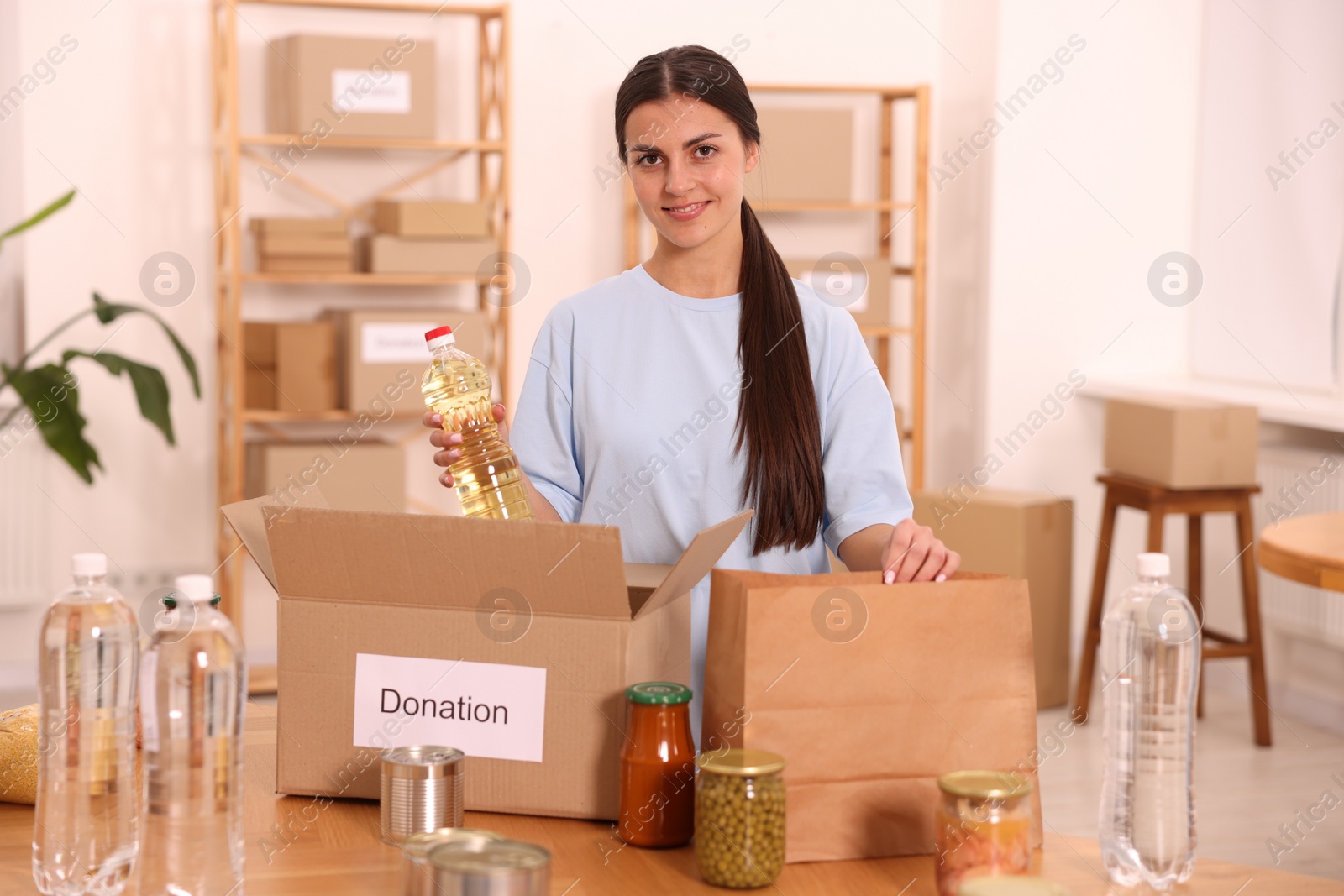 Photo of Volunteer packing food products at table in warehouse