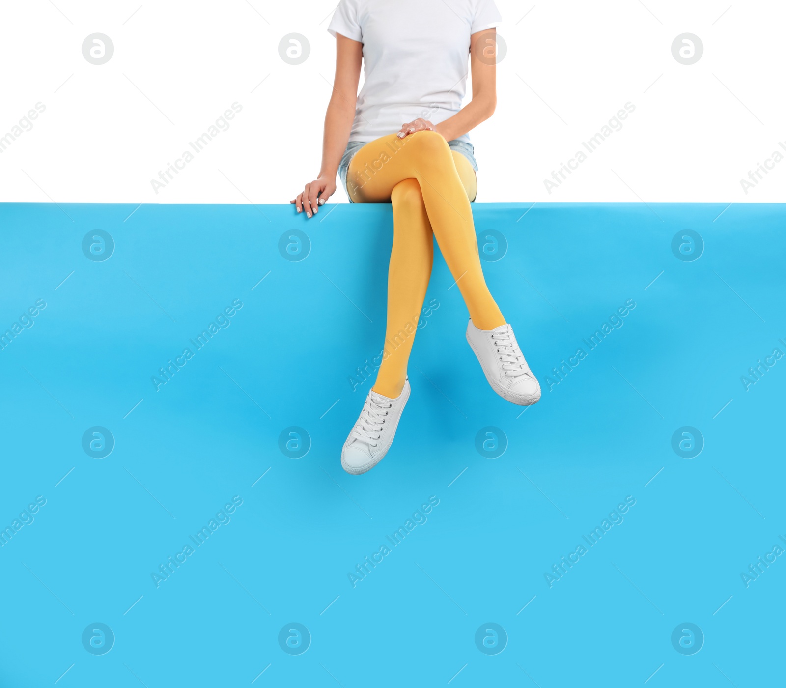 Photo of Woman wearing yellow tights and stylish shoes sitting on color background, closeup