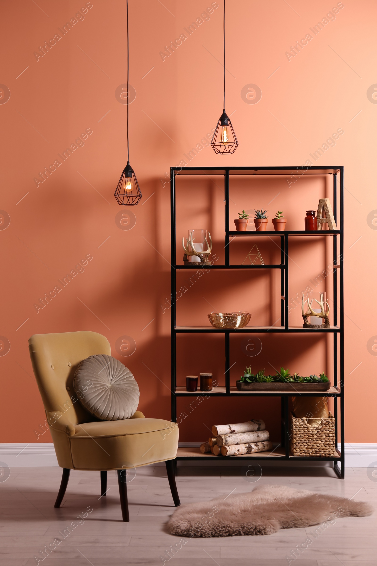 Photo of Armchair near shelving with different decor, houseplants and firewood in room. Interior design