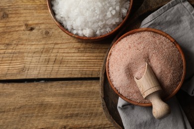 Photo of Different natural salt on wooden table, flat lay. Space for text