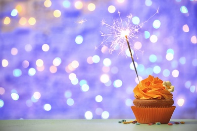Photo of Birthday cupcake with sparkler against blurred lights