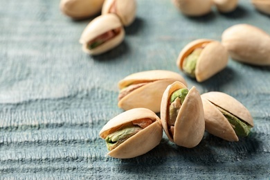 Photo of Organic pistachio nuts on wooden table, closeup