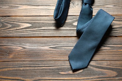 Photo of One blue necktie on wooden table, top view. Space for text