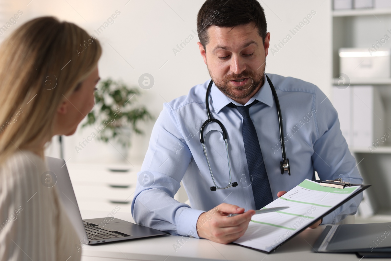 Photo of Professional doctor working with patient at white table in hospital