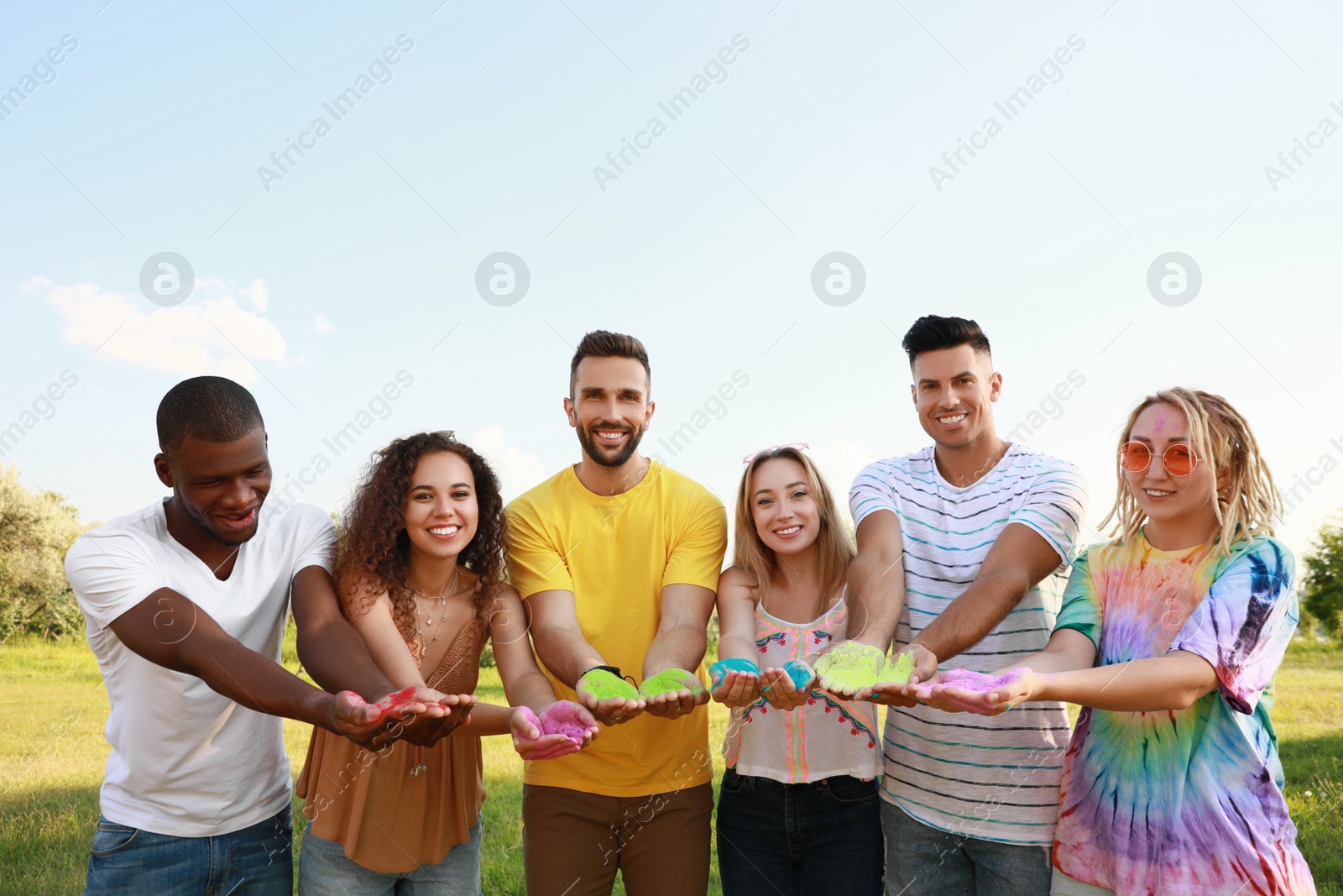 Photo of Happy friends with colorful powder dyes outdoors. Holi festival celebration