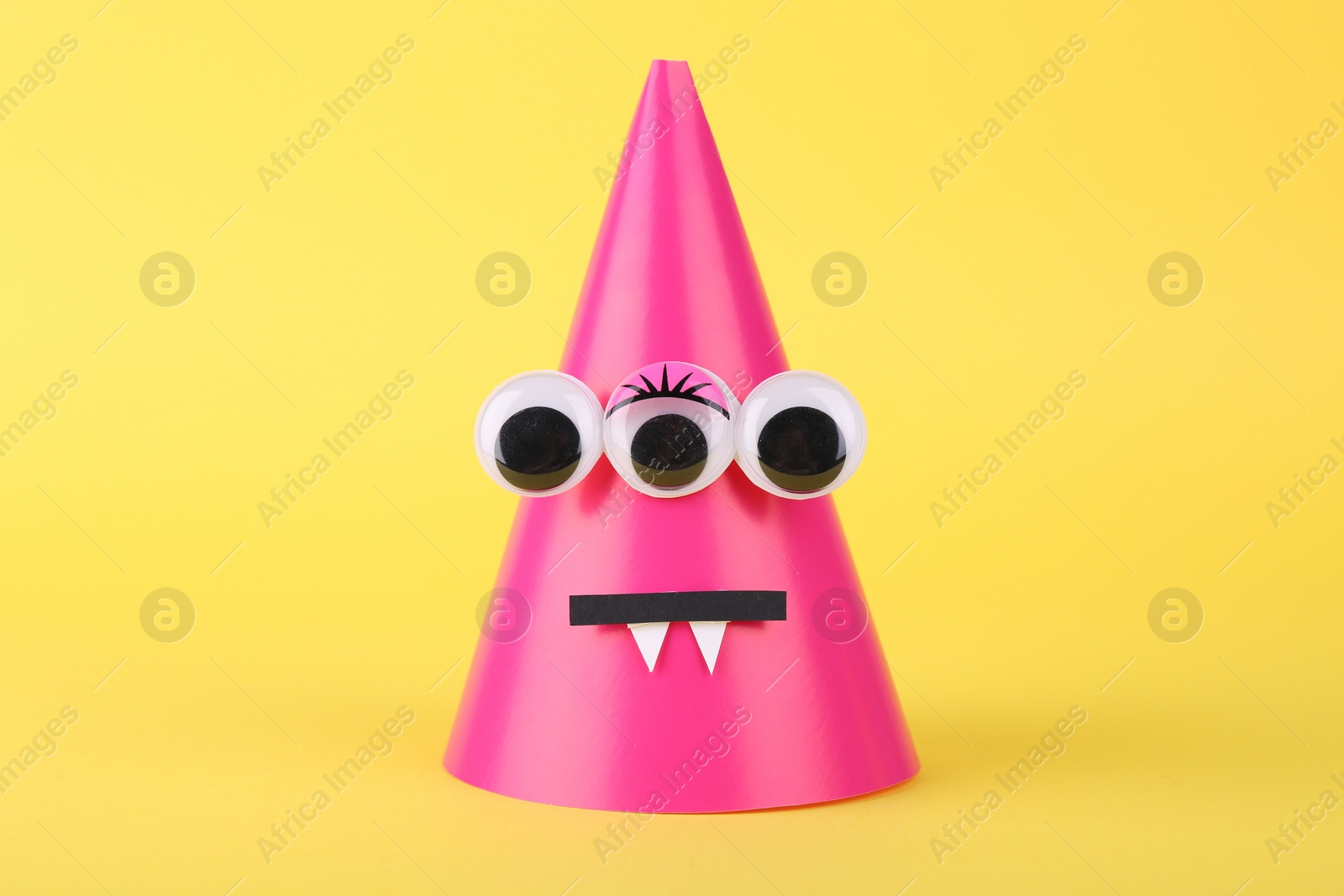 Photo of Spooky paper monster on yellow background. Halloween decoration