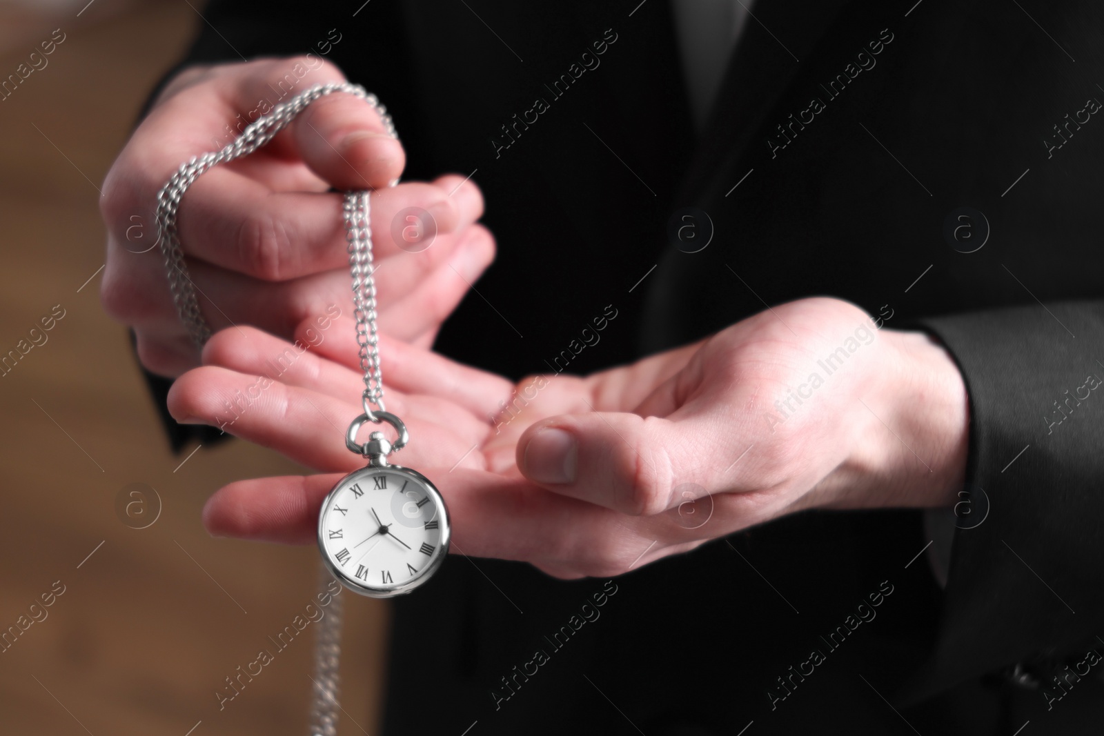 Photo of Man holding chain with elegant pocket watch on blurred background, closeup
