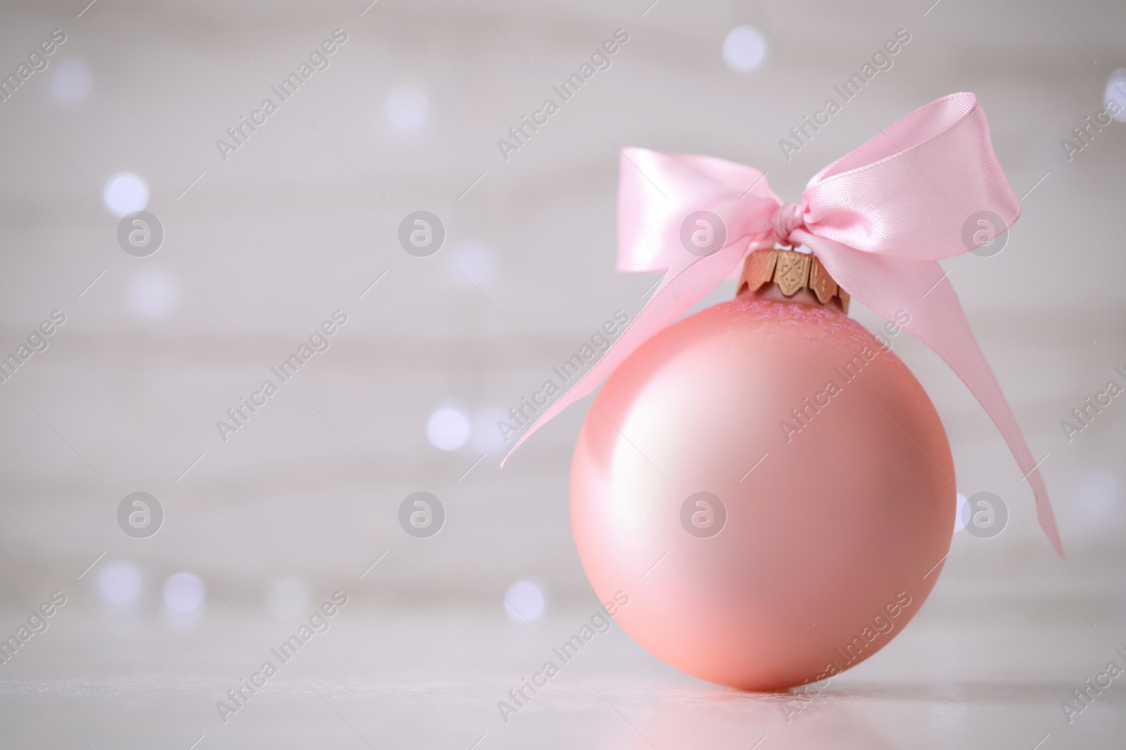 Photo of Beautiful Christmas ball on table against blurred festive lights. Space for text