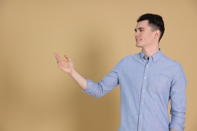 Portrait of handsome young man gesturing on beige background