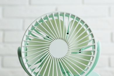 Photo of Portable fan near white brick wall, closeup. Summer heat