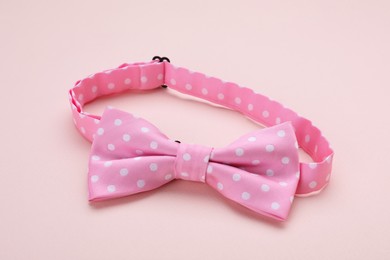 Stylish pink bow tie with polka dot pattern on beige background