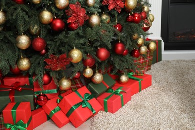 Many gift boxes under decorated Christmas tree in room