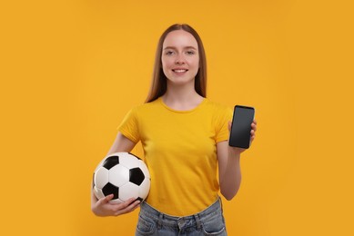 Photo of Happy sports fan with ball and smartphone on yellow background