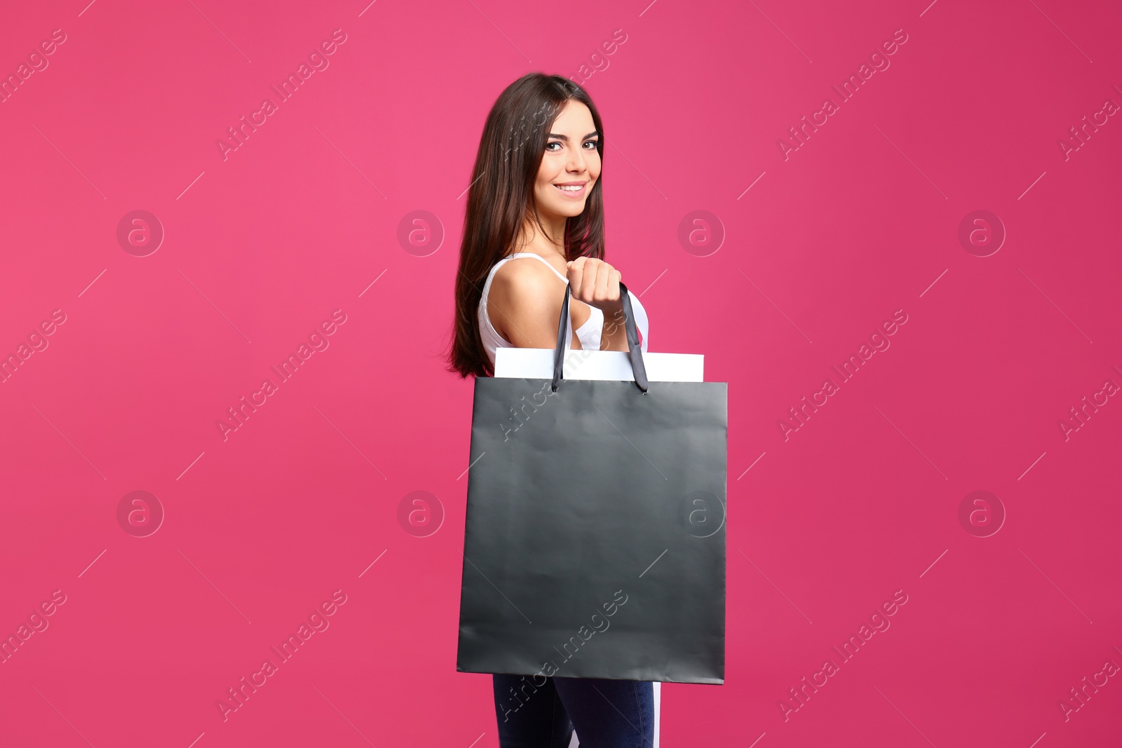 Photo of Portrait of young woman with paper bags on pink background