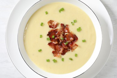 Photo of Tasty potato soup with bacon and green onion in bowl on white table, top view