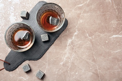 Glasses with liquor and whiskey stones on grey background, top view