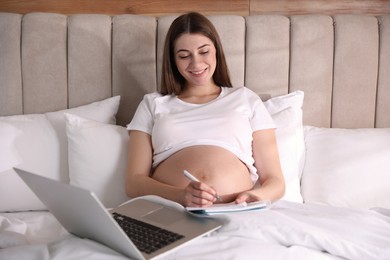 Pregnant woman working on bed at home. Maternity leave