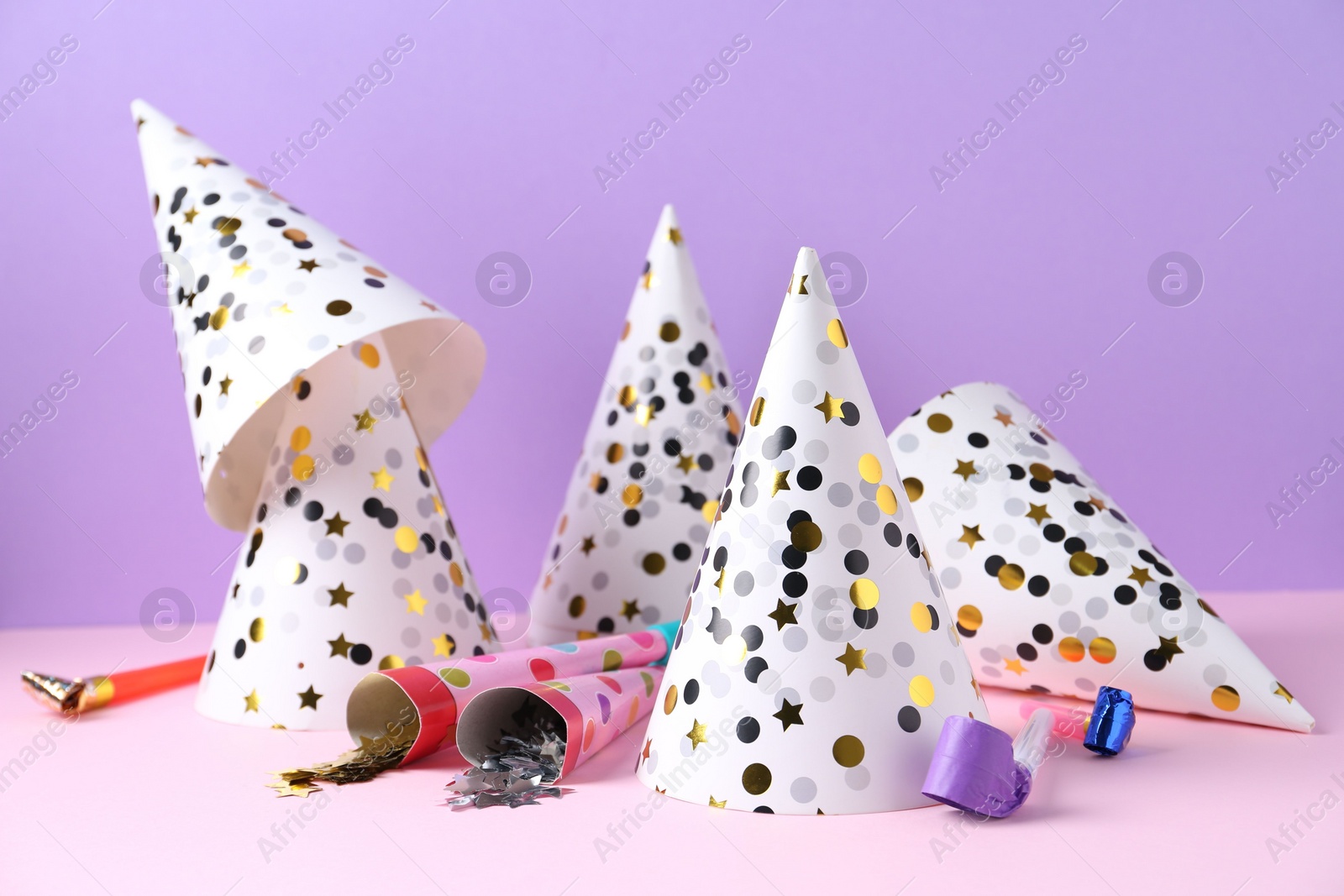 Photo of Party hats, confetti and blowers on color background