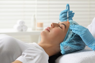 Doctor giving facial injection to young woman in clinic. Cosmetic surgery