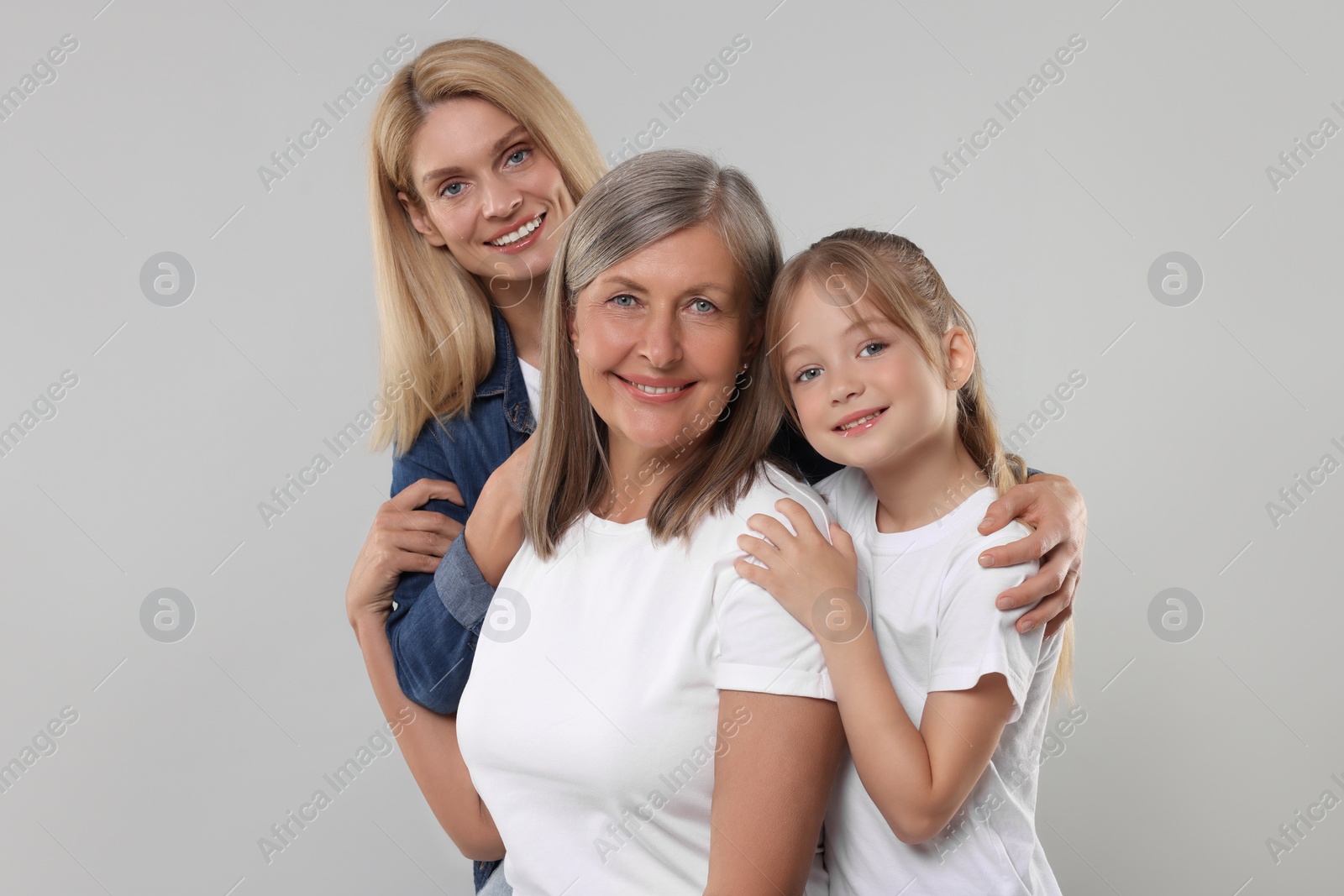 Photo of Three generations. Happy grandmother, her daughter and granddaughter on light gray background