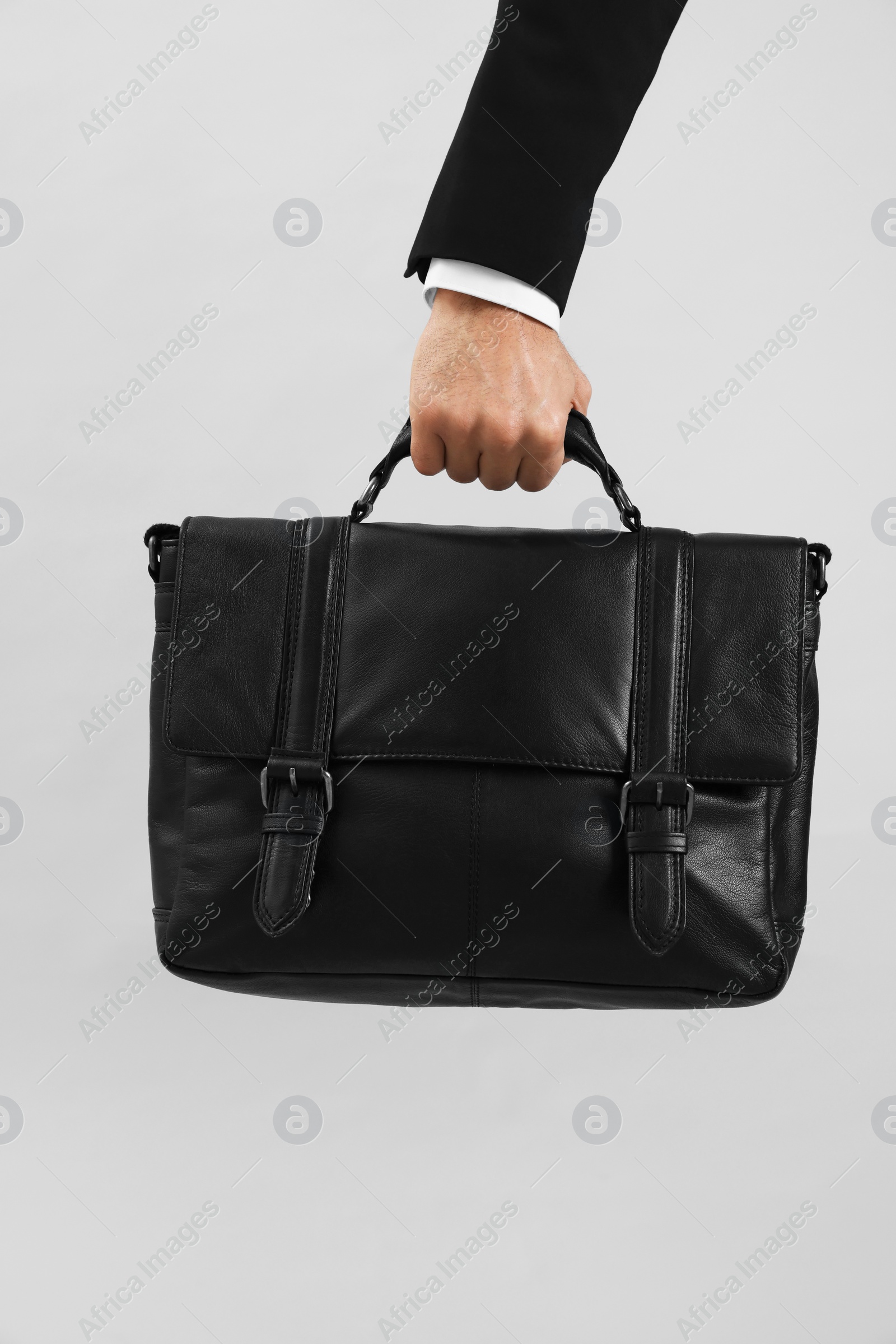 Photo of Man holding stylish leather briefcase on light grey background, closeup