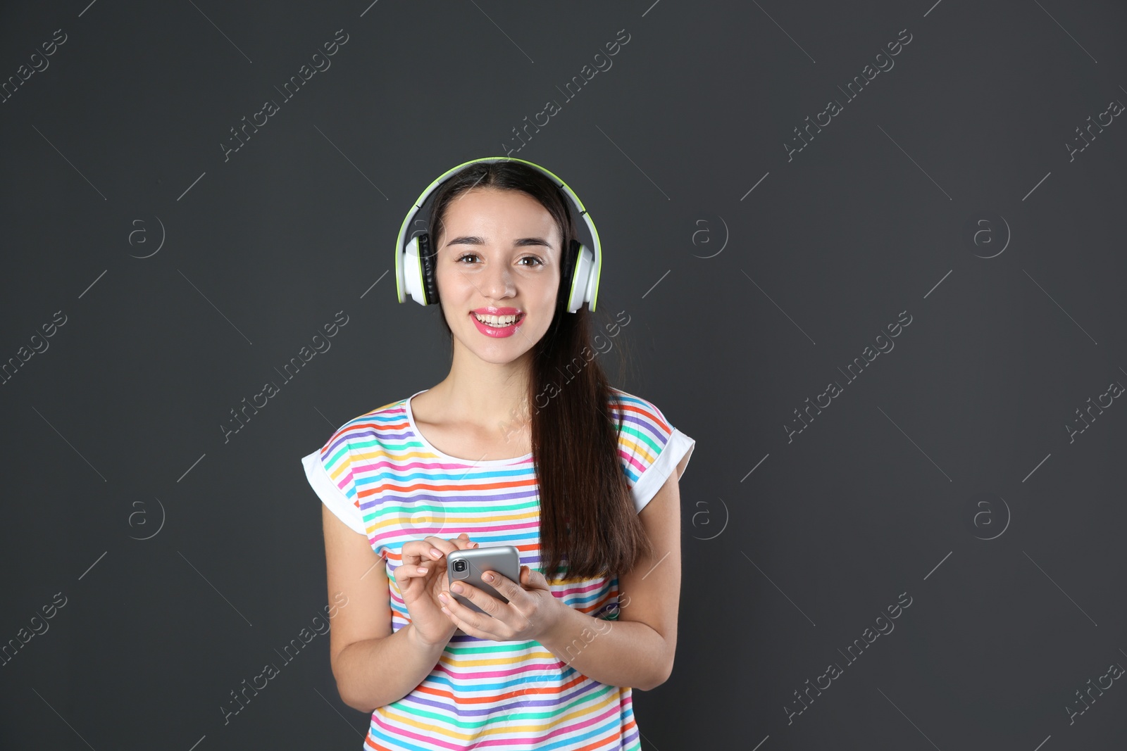 Photo of Beautiful young woman listening to music with headphones on black background