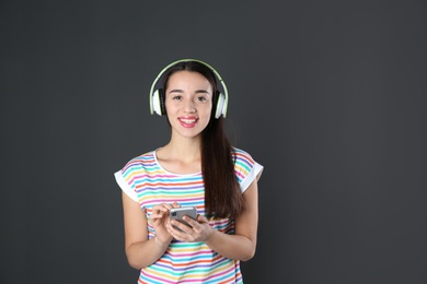 Beautiful young woman listening to music with headphones on black background