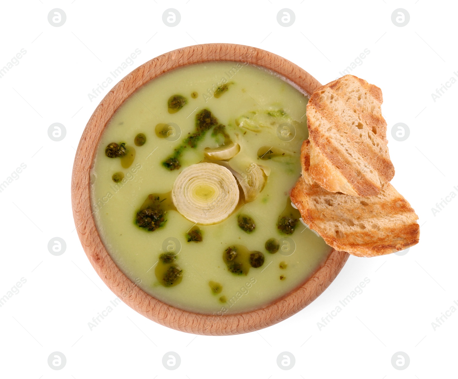 Photo of Bowl of delicious leek soup and croutons isolated on white, top view