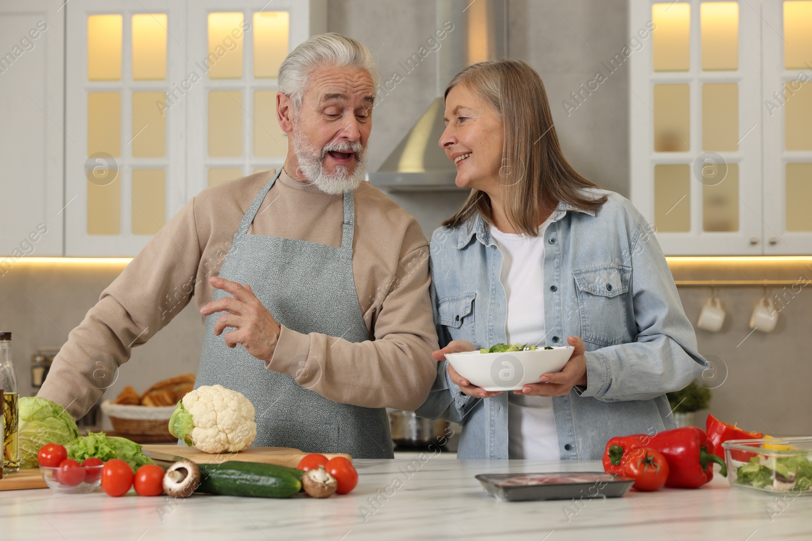 Photo of Happy senior couple cooking together in kitchen