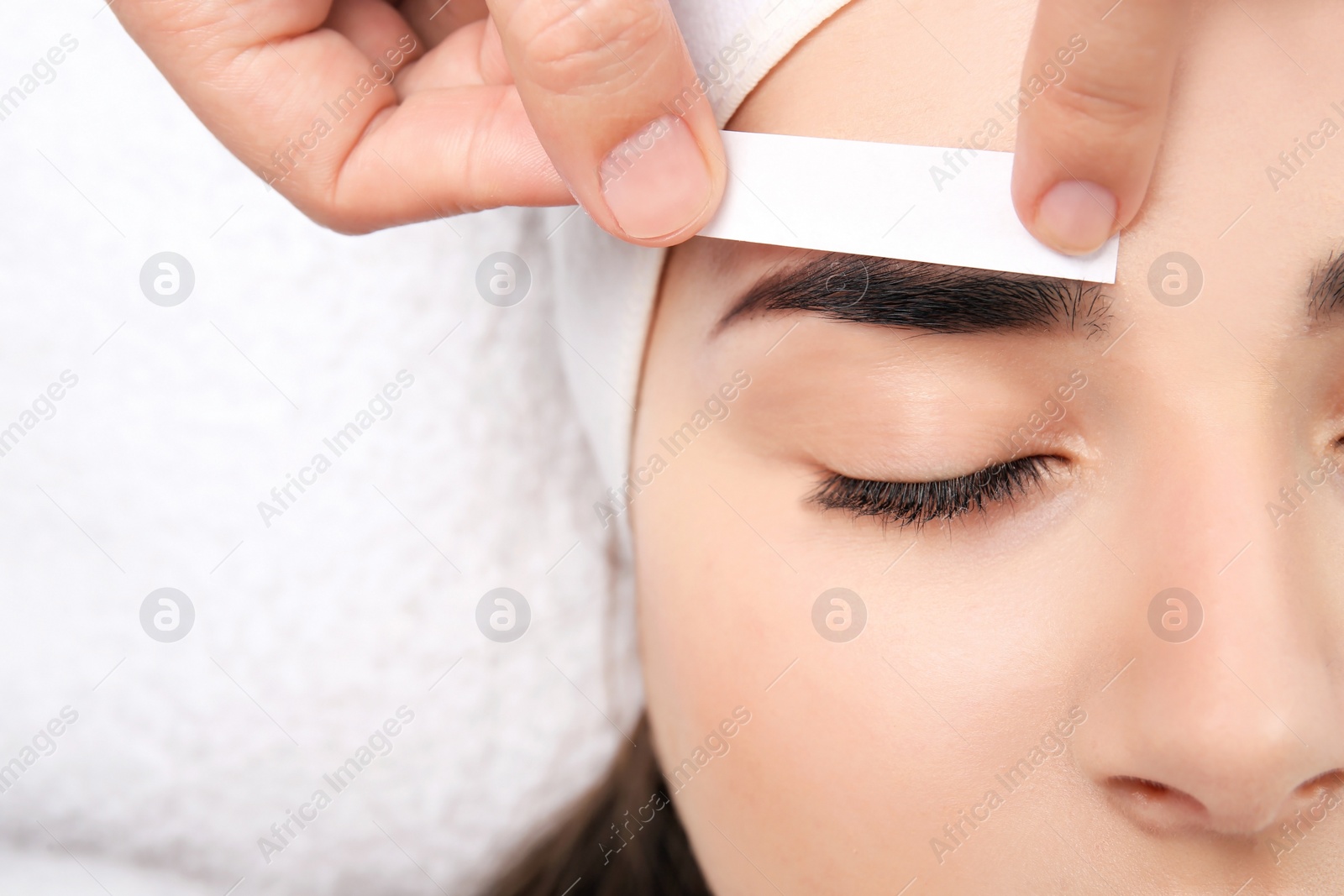 Photo of Young woman having professional eyebrow correction procedure, closeup