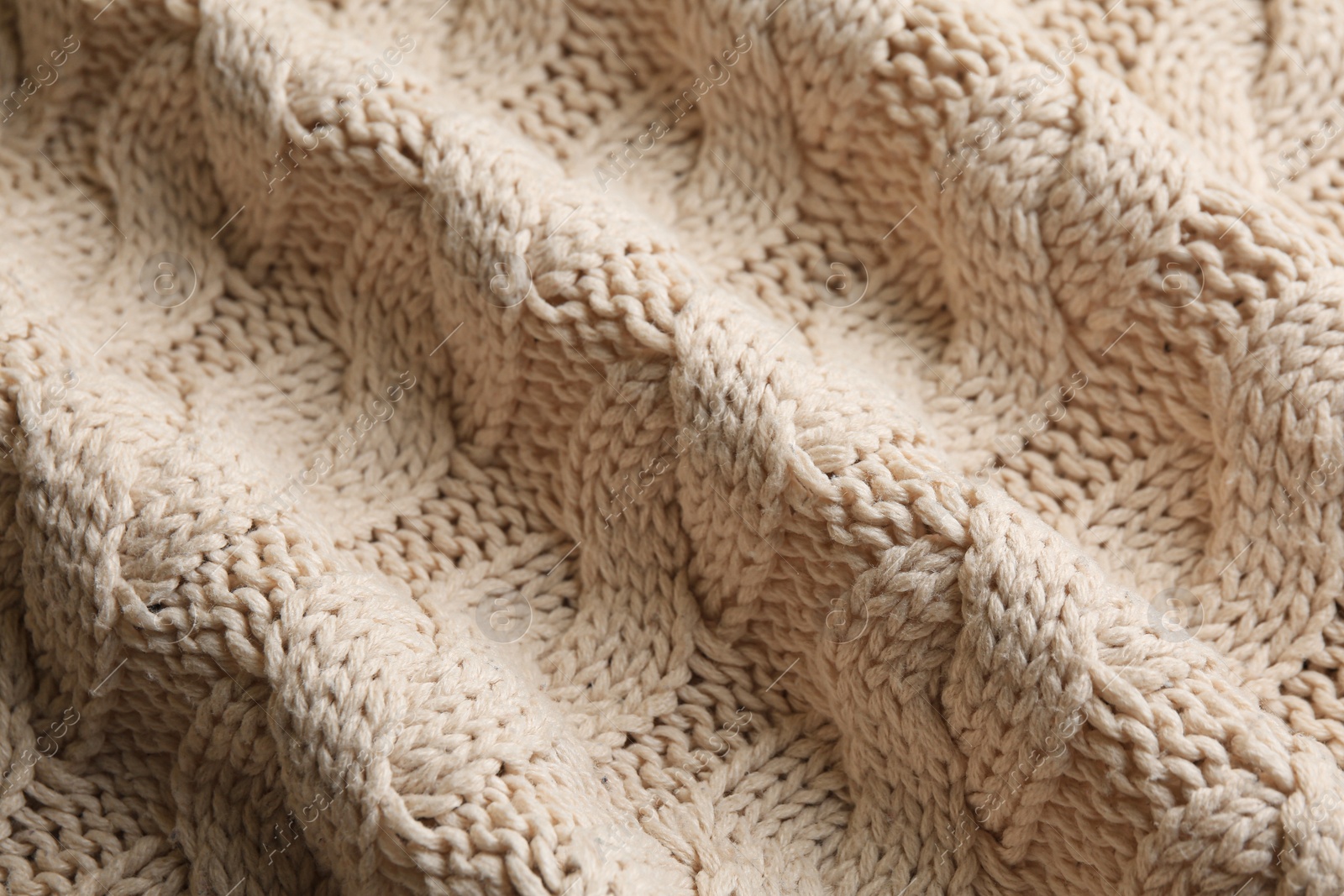 Photo of Beige knitted fabric with beautiful pattern as background, closeup