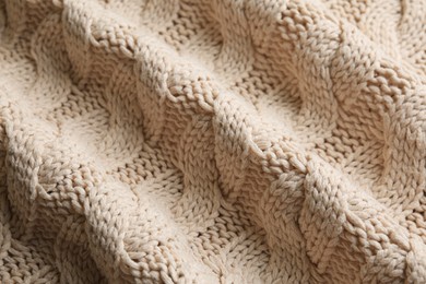 Beige knitted fabric with beautiful pattern as background, closeup