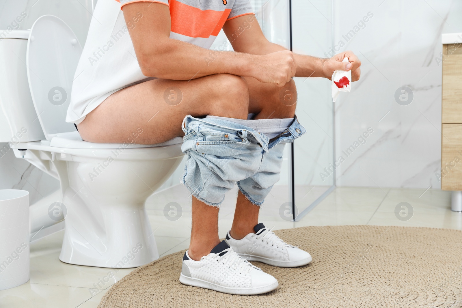 Photo of Man holding toilet paper with blood stain in rest room, closeup. Hemorrhoid concept