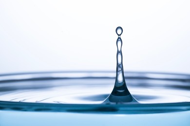 Photo of Splash of clear water with drops on light grey background, closeup. Space for text