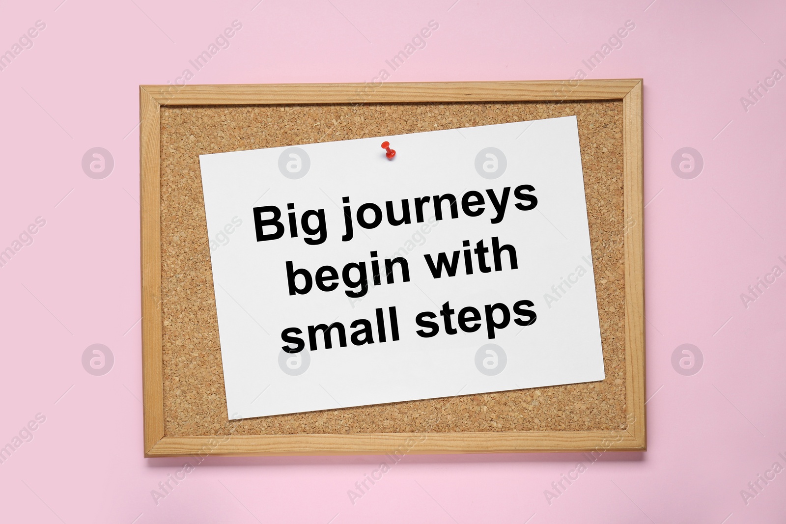 Photo of Corkboard with pinned message Big Journeys Begin With Small Steps on pink background, top view. Motivational quote