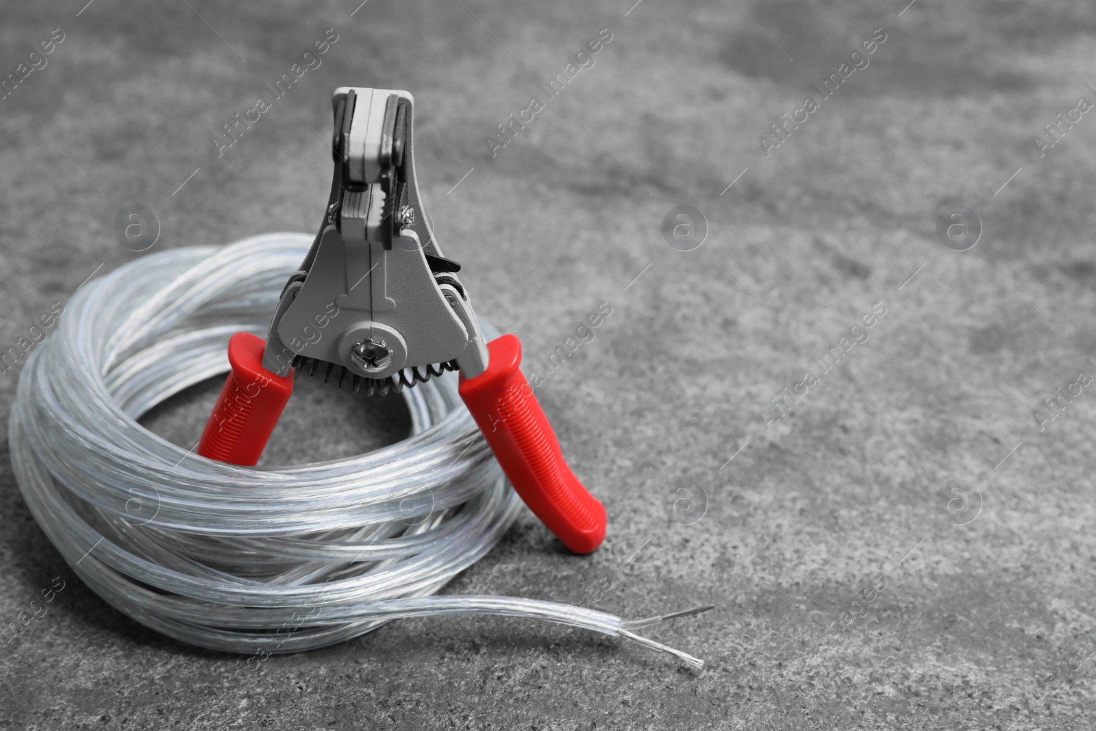 Photo of Cutters and cable with stripped wire on light gray textured table, space for text