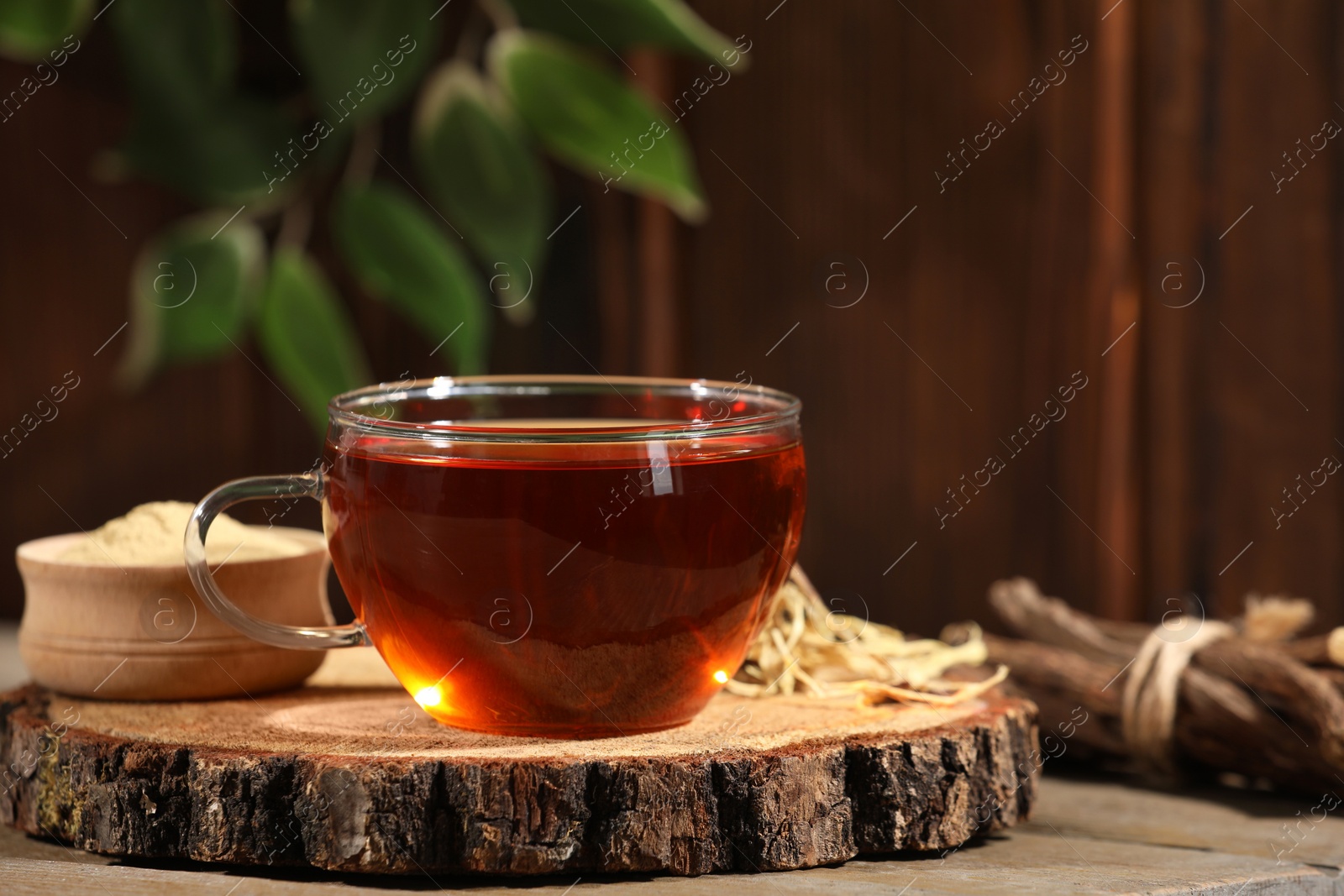 Photo of Aromatic licorice tea in cup on wooden table, space for text