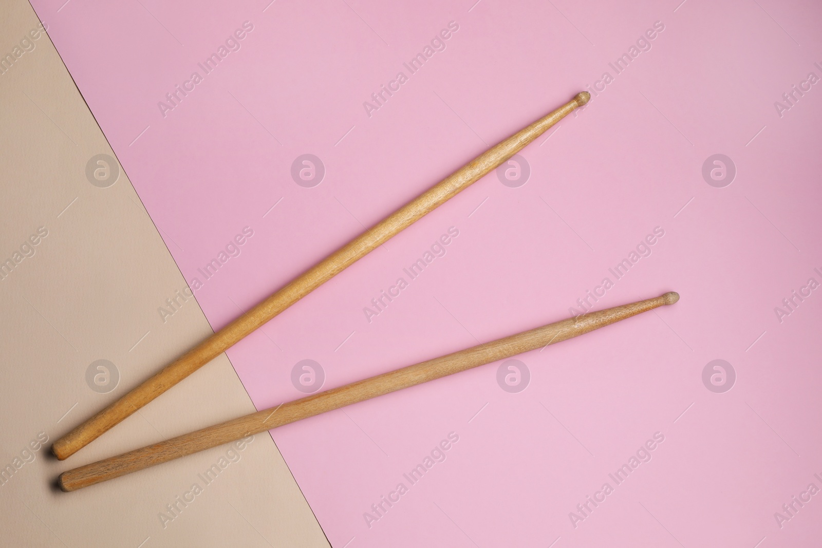 Photo of Two wooden drum sticks on color background, top view