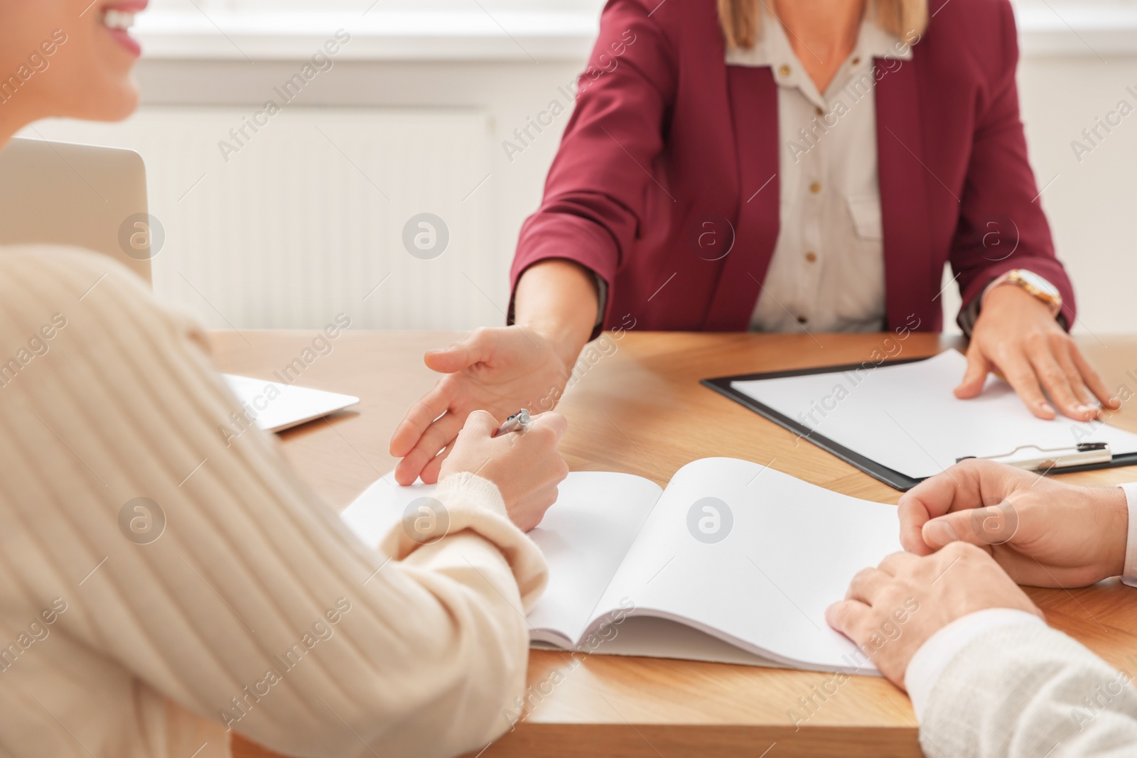 Photo of Real estate agent and couple signing contract at table in new apartment, closeup