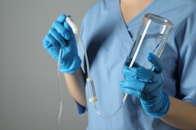 Photo of Nurse with IV infusion set on grey background, closeup