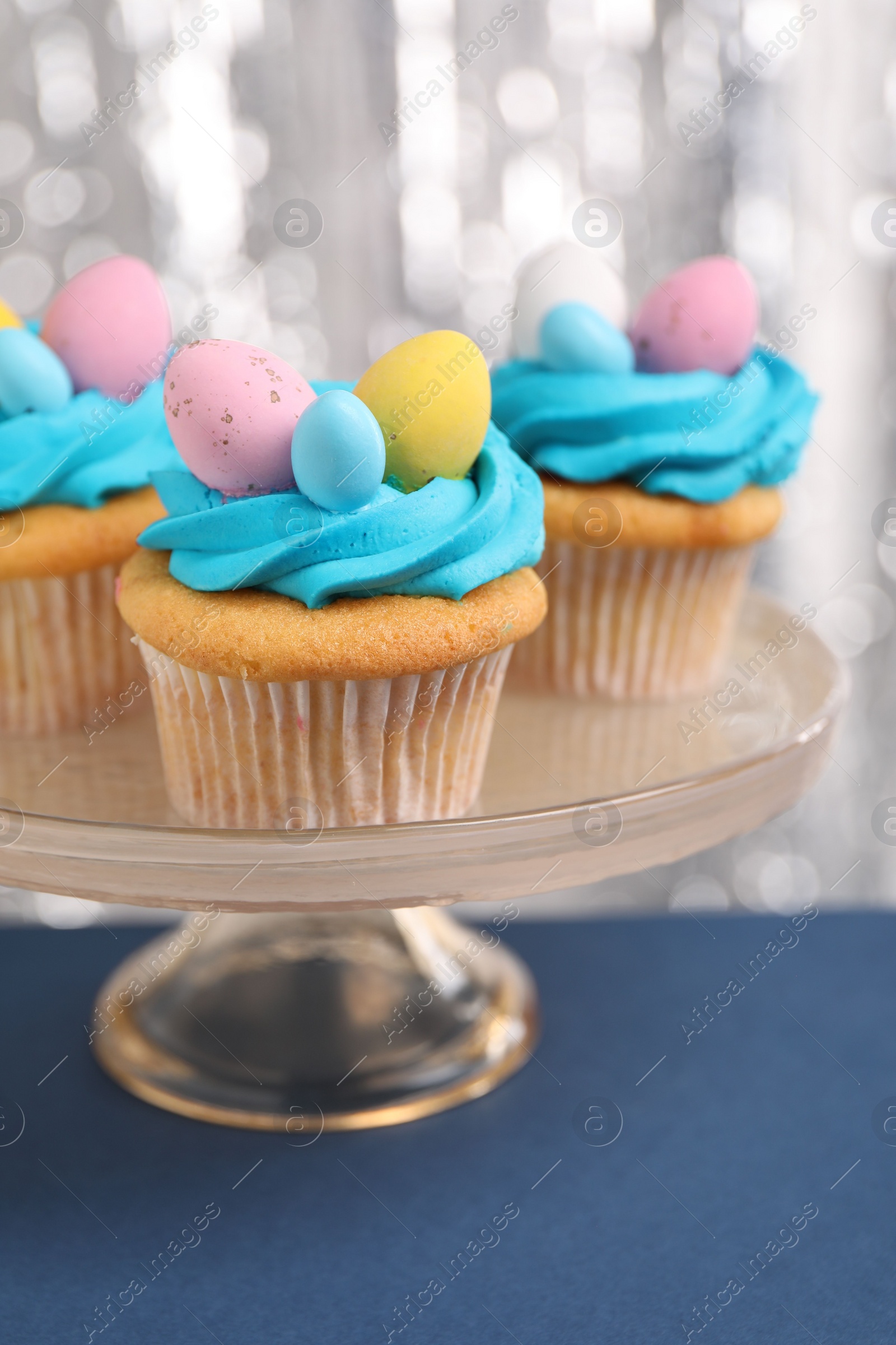 Photo of Tasty decorated Easter cupcakes on blue table, closeup