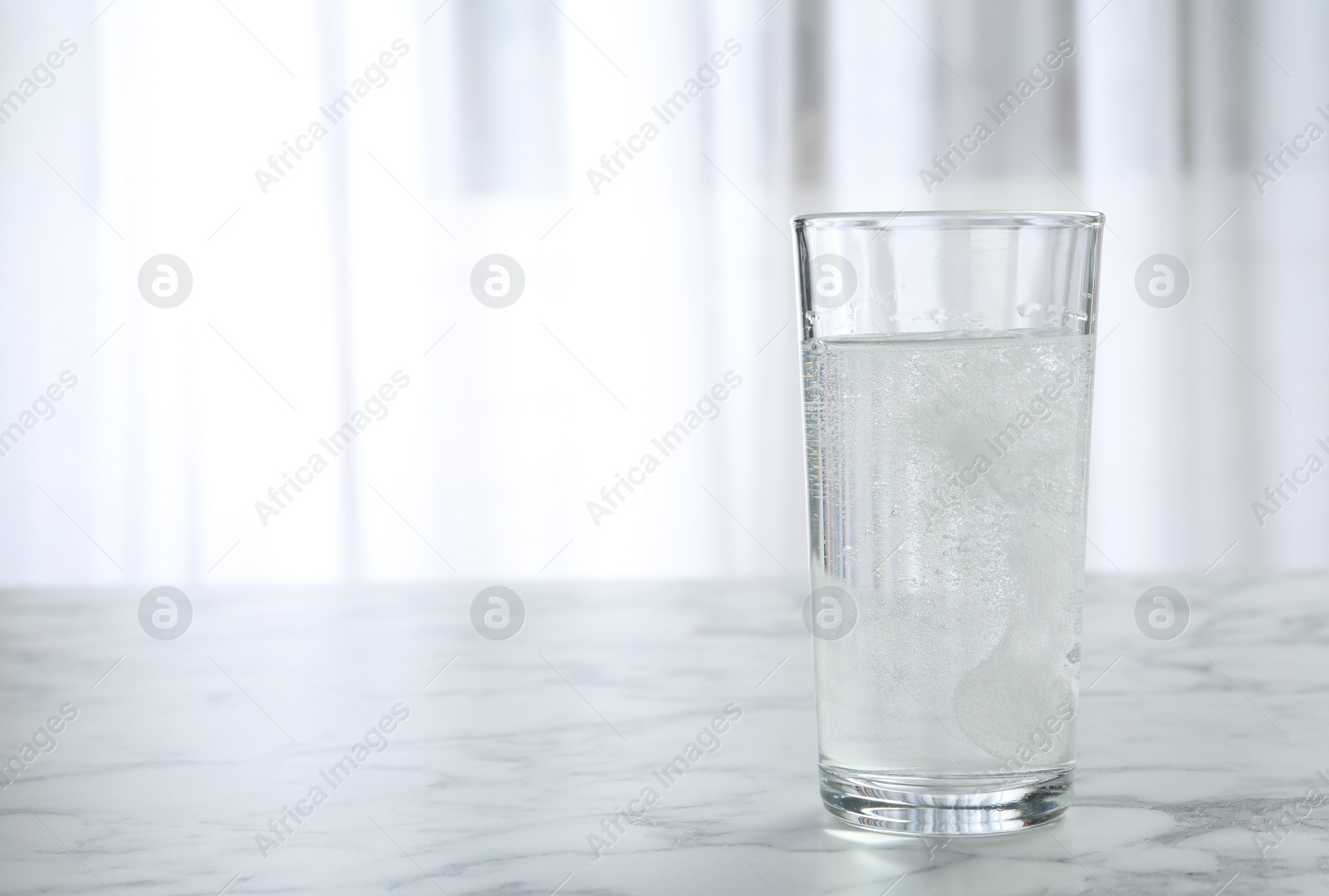 Photo of Glass of water with effervescent tablet on marble table indoors, space for text