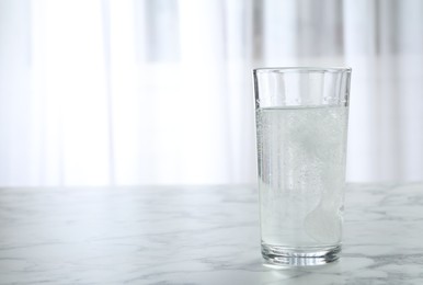 Photo of Glass of water with effervescent tablet on marble table indoors, space for text