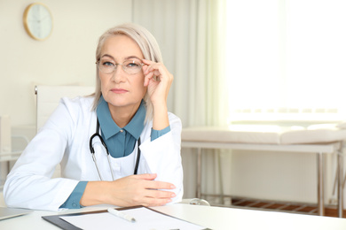 Portrait of mature female doctor in white coat at workplace