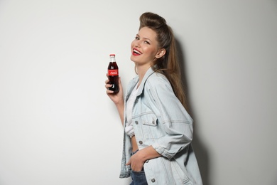 MYKOLAIV, UKRAINE - NOVEMBER 28, 2018: Young woman with bottle of Coca-Cola on white background