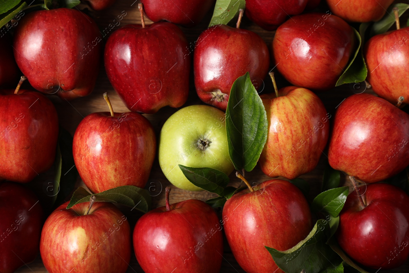 Photo of Fresh ripe apples with leaves on wooden table, flat lay